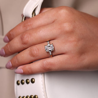 Tapered baguette side stones flanking a cushion cut diamond, creating a balanced and stunning look.