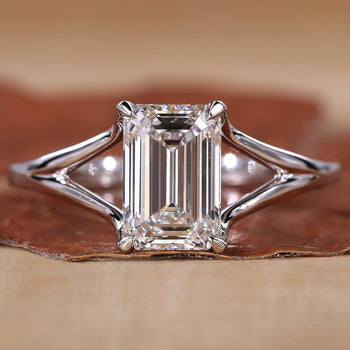 Close-up of emerald cut solitaire ring with claw prongs and white gold band.