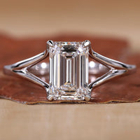 Close-up of emerald cut solitaire ring with claw prongs and white gold band.