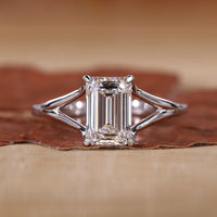 Close-up of emerald cut solitaire ring with claw prongs and white gold band.