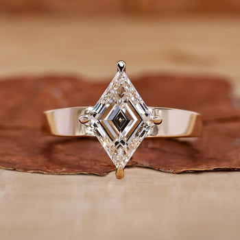 An elegant gold engagement ring featuring a stunning lozenge cut diamond as the centerpiece.