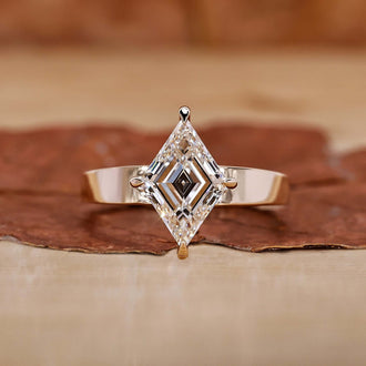 An elegant gold engagement ring featuring a stunning lozenge cut diamond as the centerpiece.