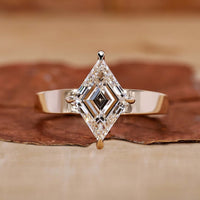 An elegant gold engagement ring featuring a stunning lozenge cut diamond as the centerpiece.