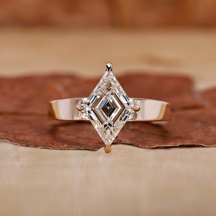 An elegant gold engagement ring featuring a stunning lozenge cut diamond as the centerpiece.