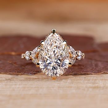 Pear cut diamond ring with hidden halo and marquise side stones.