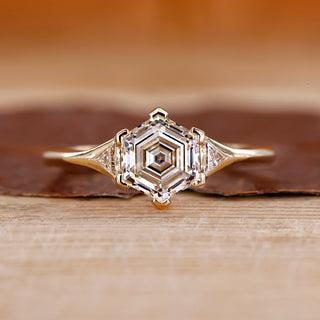 Hexagon step cut center diamond ring in yellow gold.