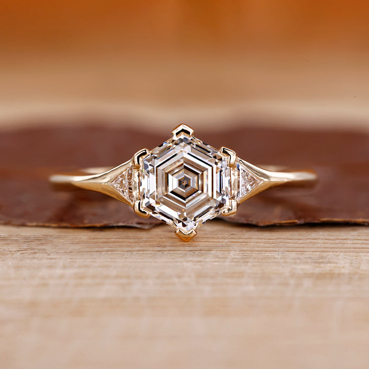 Hexagon step cut center diamond ring in yellow gold.
