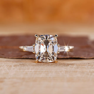 Old mine cushion cut diamond ring with tapered baguette side stones, offering a unique design.