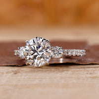 White gold filigree engagement ring with a round diamond pave band.