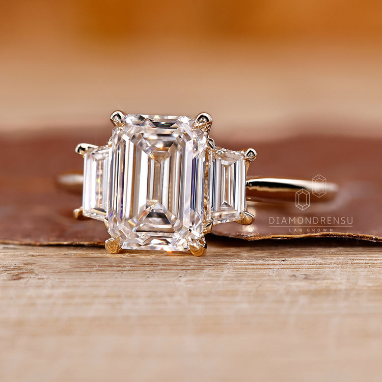 Trapezoid ring design with a striking three stone emerald cut centerpiece.