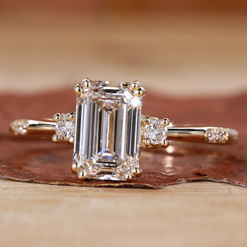 Close-up of a three stone emerald cut ring on a velvet cushion.