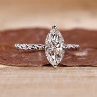 Twisted pave band engagement ring with a diamond center, offering a distinctive and detailed design.