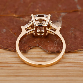 Unique engagement ring with a cushion cut diamond and tapered baguette side stones, set in yellow gold.