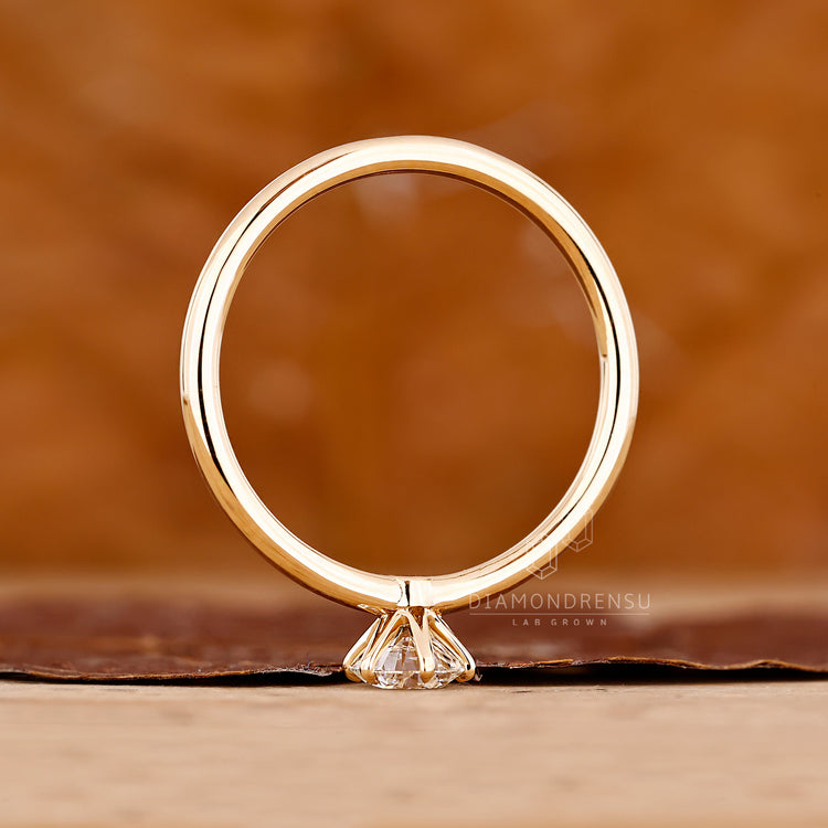 Solitaire setting round brilliant cut diamond ring in yellow gold design.