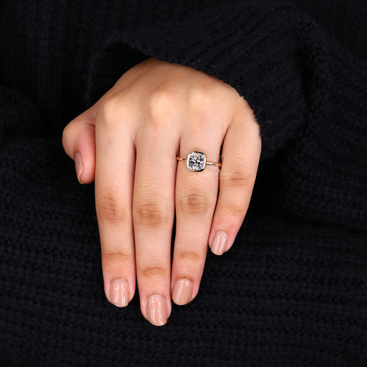 Gold solitaire engagement ring with a bezel set cushion cut diamond for elegance.