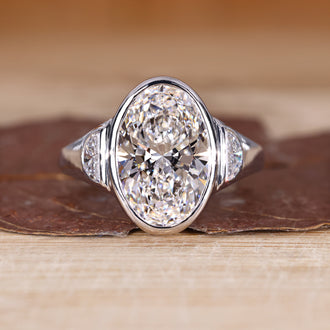3 stone diamond ring with oval cut center diamond and half moon cut side stones.