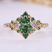 Green marquise engagement ring with trillion side stones and emerald gemstone.