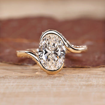 Oval cut diamond ring with half bezel and hidden pavé setting.