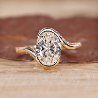 Oval cut diamond ring with half bezel and hidden pavé setting.