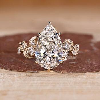Pear cut engagement ring with nature inspired design and round side stones.
