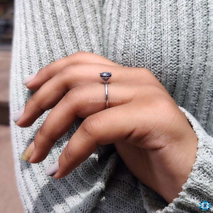 Solitaire setting engagement ring with blue moissanite.