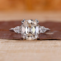 Cushion old mine cut center with pear cut side diamonds and knife edge shank.