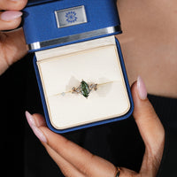 Marquise side stones frame the green marquise center stone.