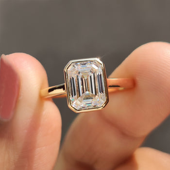 Emerald cut bezel set ring with a sleek and modern design.