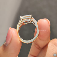 East to west ring setting with emerald cut moissanite and yellow gold accents.