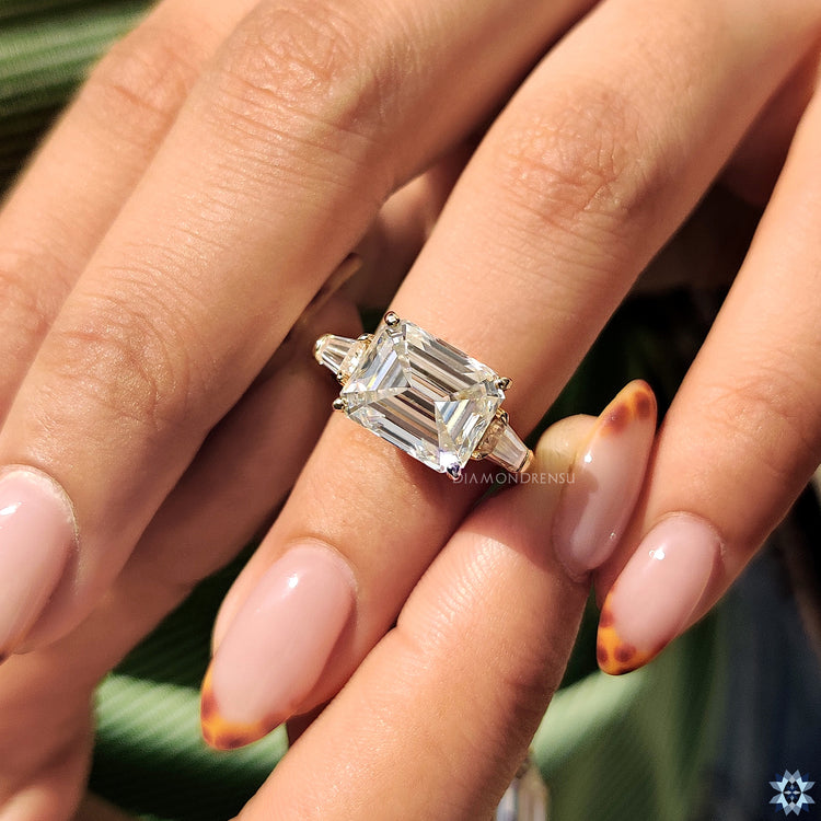 Handmade jewelry featuring an emerald cut moissanite engagement ring with tapered baguette stones.
