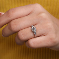 Simple engagement ring with two pear side diamonds and white gold setting.