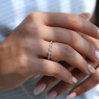 Twisted wedding band with custom white gold design and round diamonds in full eternity setting.