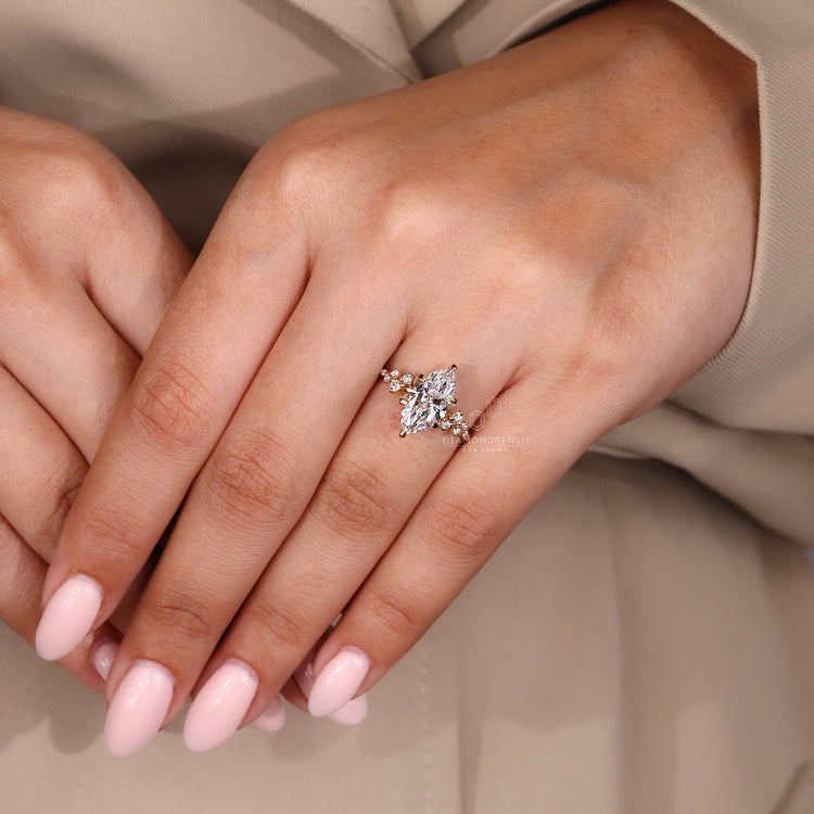 Diamond ring with marquise and round diamond side stones in a cluster setting with 6 claw prong setting.