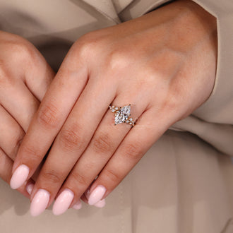 Diamond ring with marquise and round diamond side stones in a cluster setting with 6 claw prong setting.