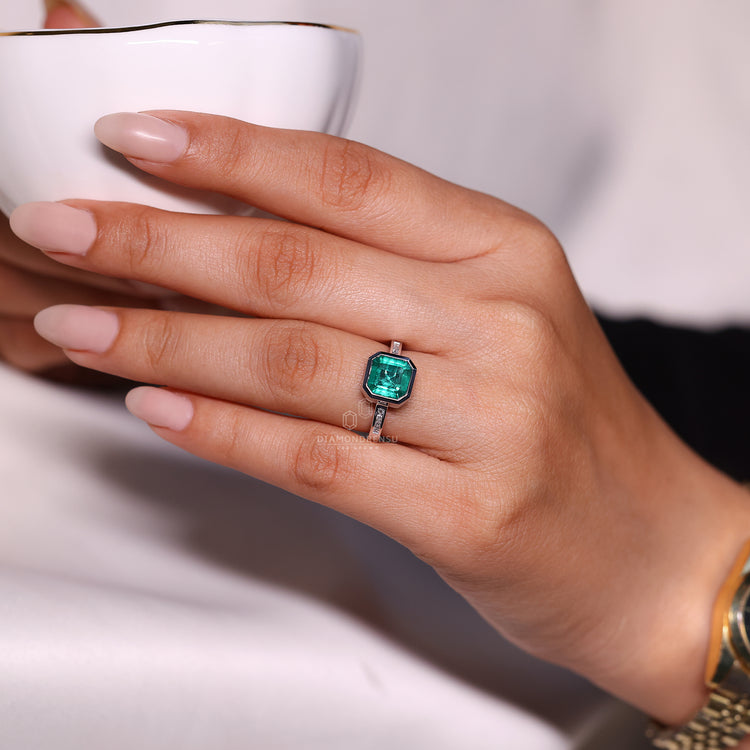 Bezel set emerald gemstone engagement ring.