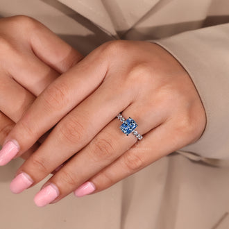 Diamondrensu ring featuring blue diamond cushion cut and 4 prong setting.