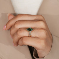 Green engagement ring with baguette and round side stones.