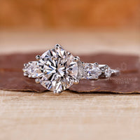 Unique engagement ring featuring round and pear side stones.