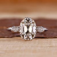 Vintage engagement ring with cushion old mine cut diamond and round sides.