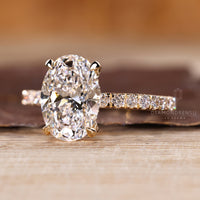 Oval cut engagement ring with round cut hidden halo and side stones.