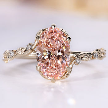 Oval engagement ring with pink center diamond and round side stones.