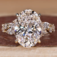 Oval diamond ring with cluster setting and side stones.
