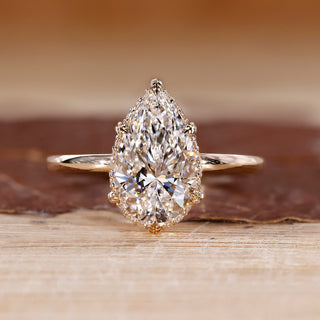 Pear cut diamond ring featuring hidden halo design and leaf style prong setting.