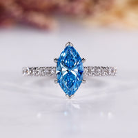 Marquise cut ring with blue diamond and pave setting in white gold.