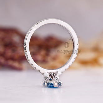 V shaped prong ring with marquise cut blue diamond in pave setting.