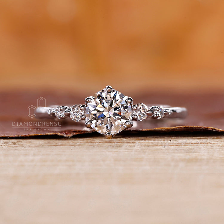 Lab grown diamond set in a diamond ring with tapered shank band, round cut side stones, and 6 round prong setting.