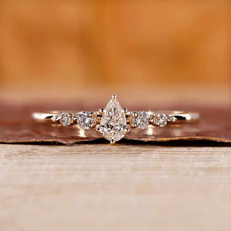 Yellow gold ring with pear cut center and round cut side stones in shared prong.