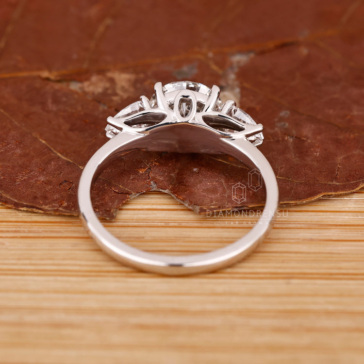Buy custom lab-grown three stone engagement ring with pear side diamonds.