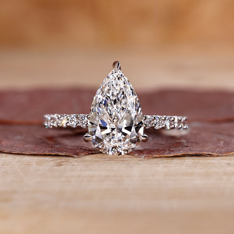 Pear shaped diamond ring with pave band in white gold.