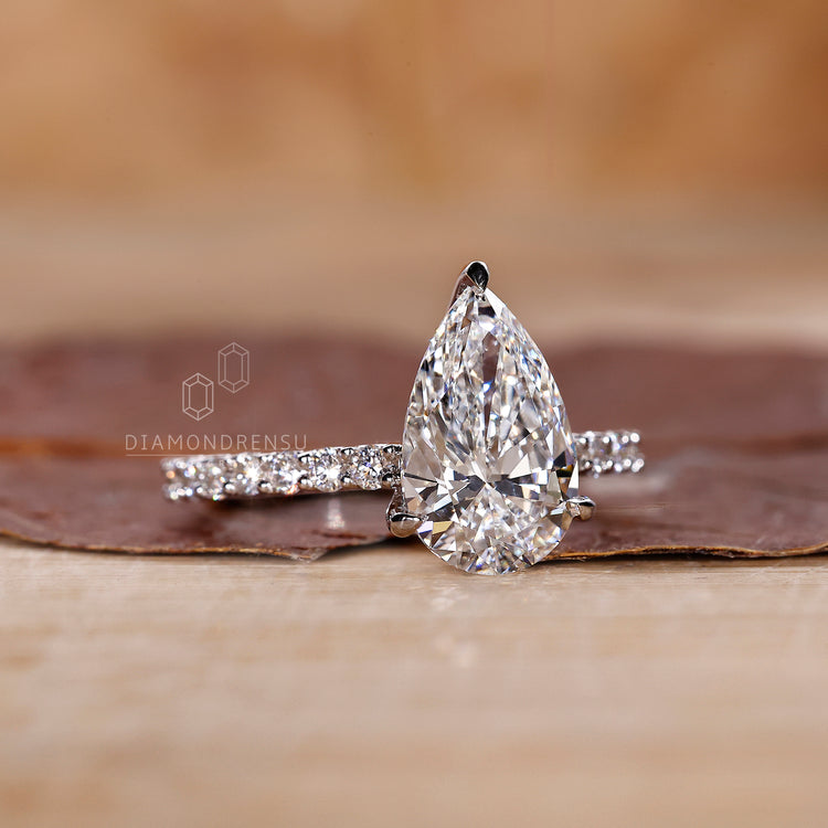 Diamondrensu engagement ring with pear cut and small round side stones.